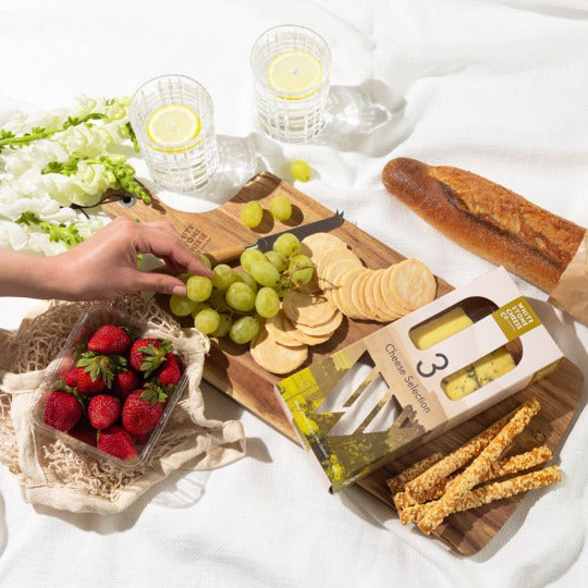 Wooden board with bread, strawberries, grapes, crackers and the 3 Cheese platter pack